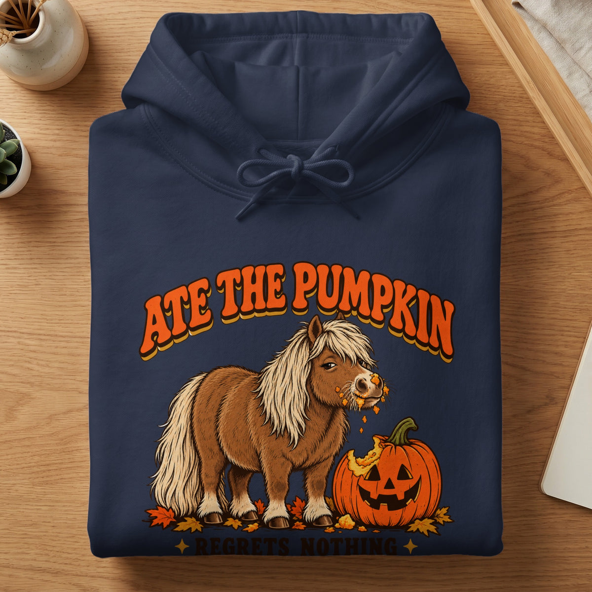 Navy hoodie with graphic of a pony eating a pumpkin, text "Ate The Pumpkin Regrets Nothing".