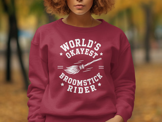 Maroon sweatshirt with white text "World's Okayest Broomstick Rider" and a broom illustration.