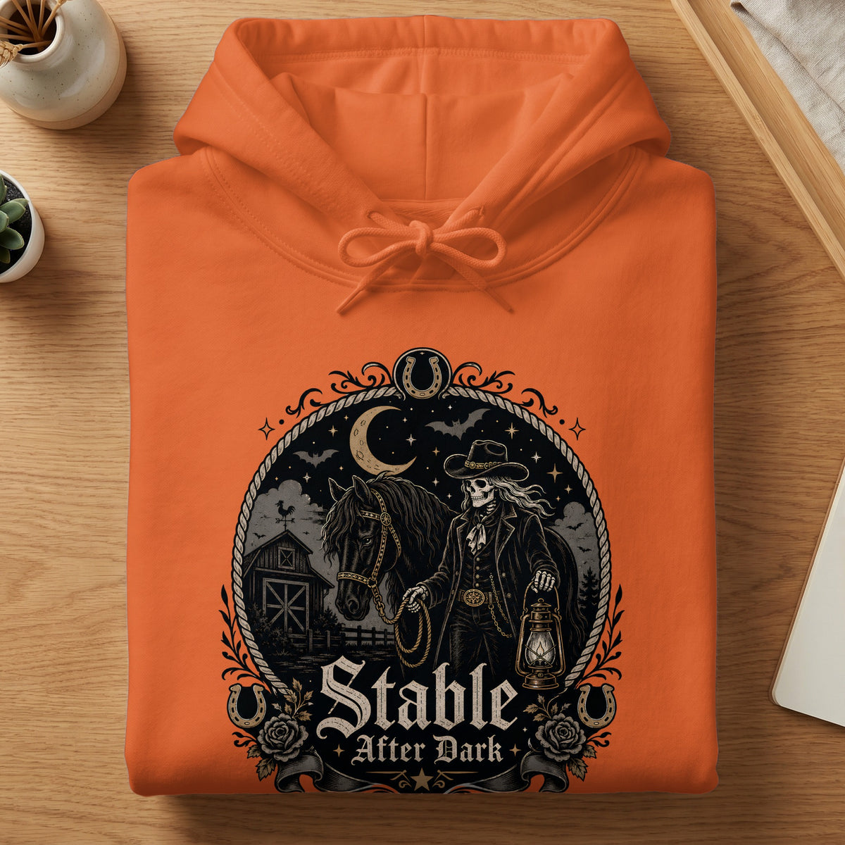 Orange hoodie with "Stable After Dark" graphic featuring a skeleton, horse, barn, and lantern.