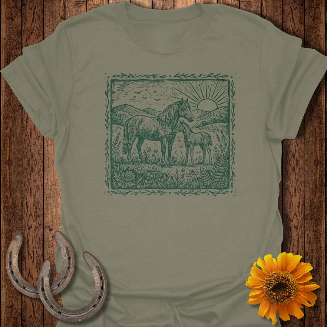 Green horse and foal illustration on a tan t-shirt, with horseshoes and sunflower.