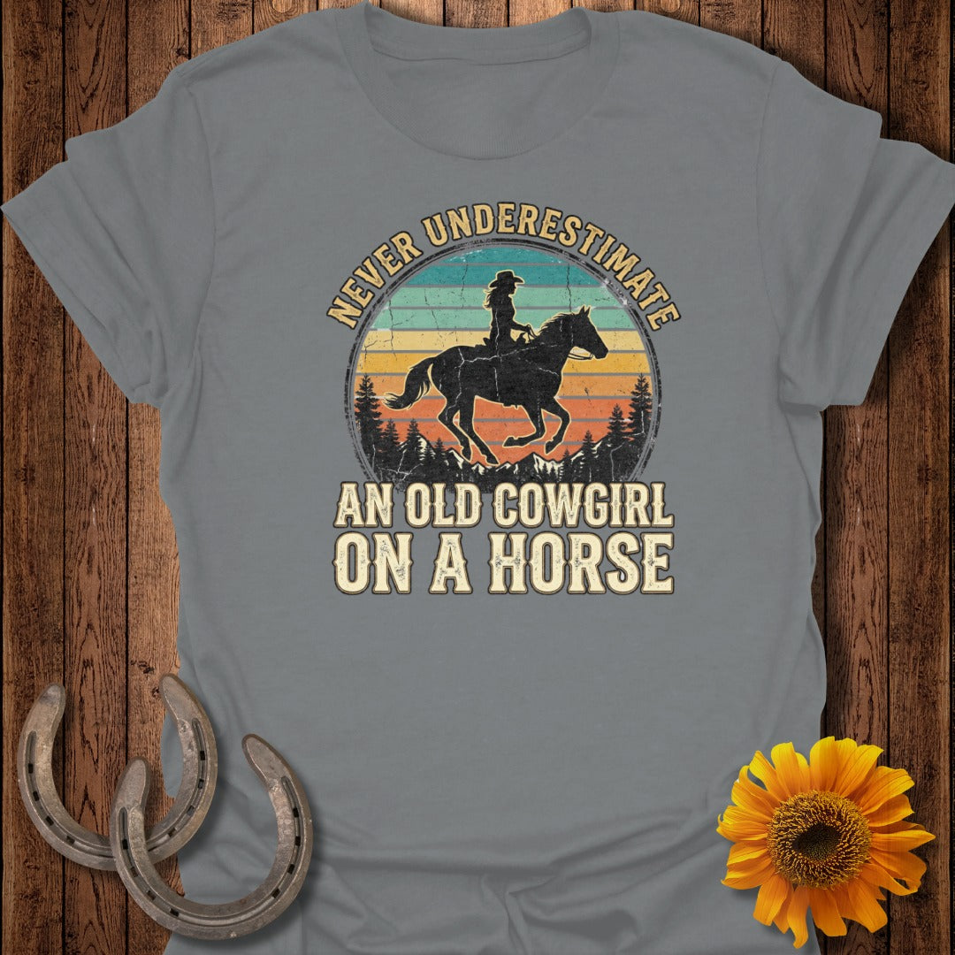 Vintage sunset graphic with cowgirl on horse and text: Never Underestimate An Old Cowgirl On A Horse.
