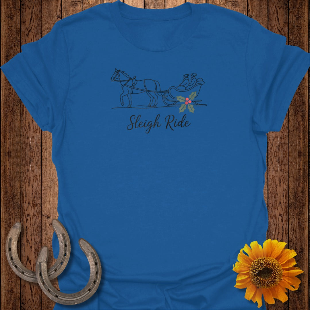 Blue t-shirt with a line drawing of a horse pulling a sleigh with two figures and holly.