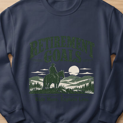 Dark blue sweatshirt with "Retirement Goals Ride More. Explain Less." text and cowboy on horse.