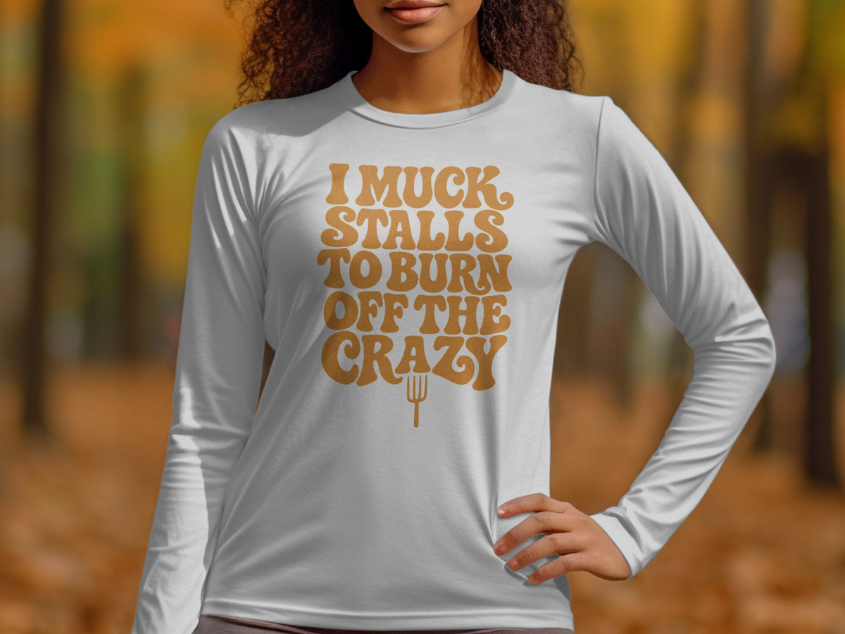White long-sleeve shirt with text "I Muck Stalls To Burn Off The Crazy"