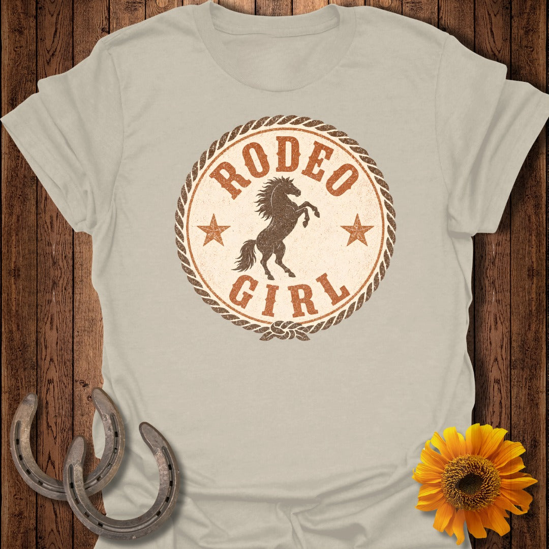 T-shirt graphic with a horse, stars, "Rodeo Girl" text, and rope border.