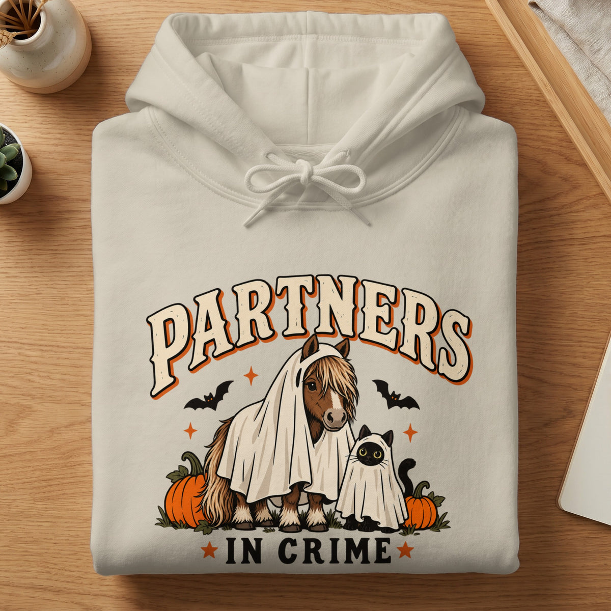 Cream hoodie with "Partners In Crime" text, a horse and cat in ghost costumes, pumpkins, and bats.