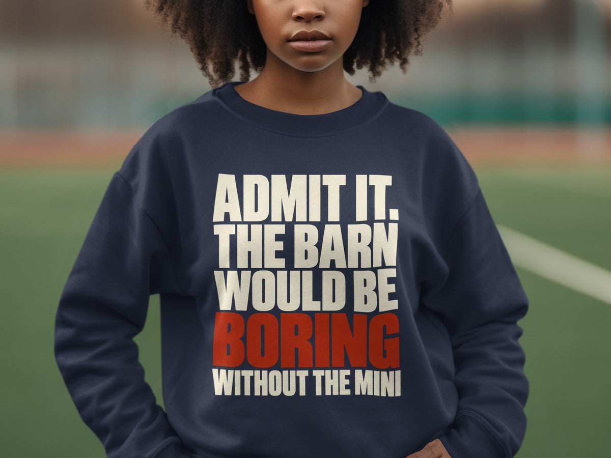 A person wearing a dark blue sweatshirt featuring white and red text stating, ADMIT IT. THE BARN WOULD BE BORING WITHOUT THE MINI.