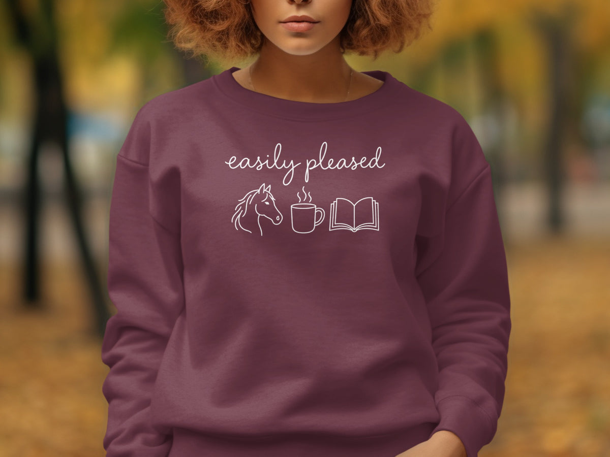 Maroon sweatshirt with white text "easily pleased" and line art of a horse, coffee cup, and book.