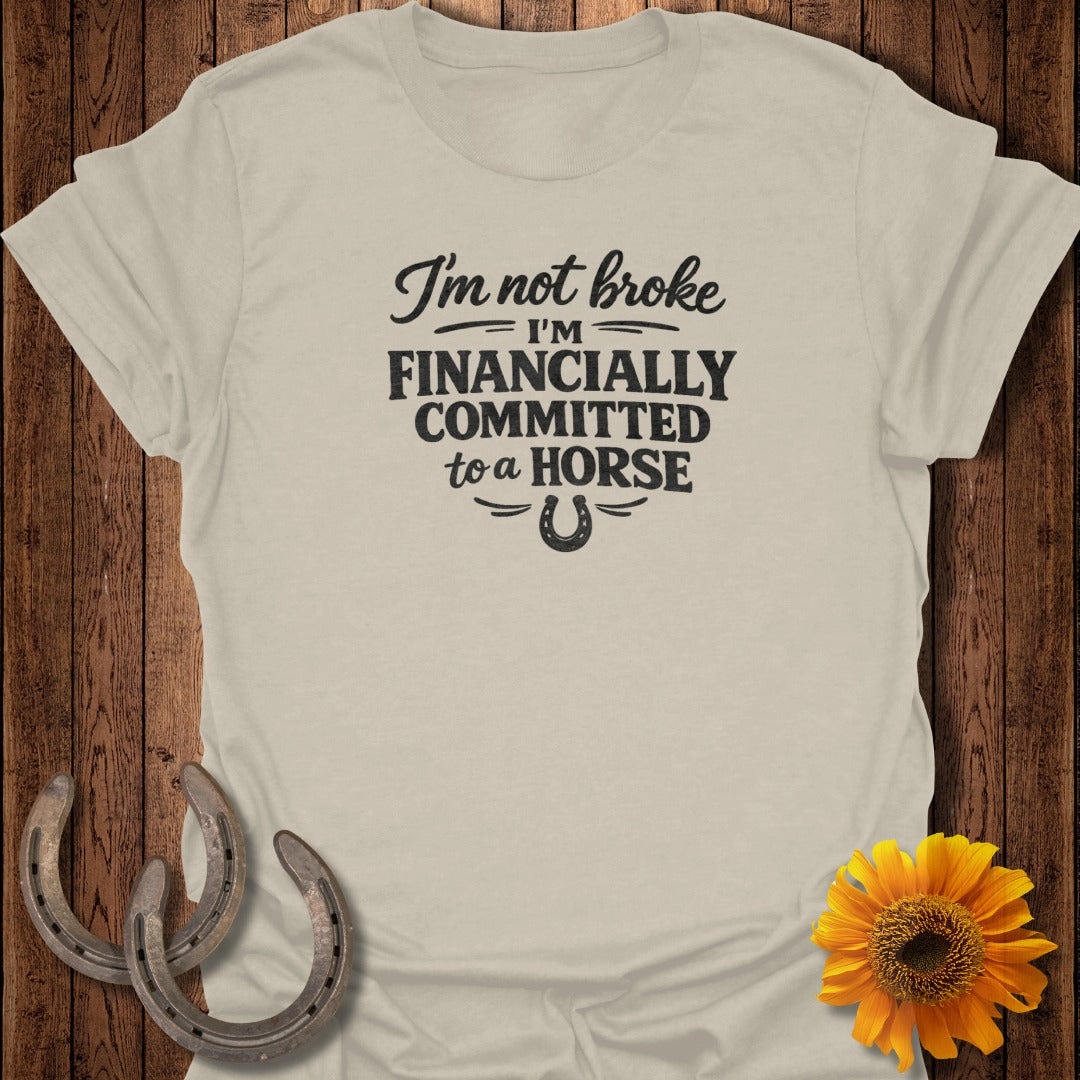 Light tan t-shirt with "I'm not broke I'm FINANCIALLY COMMITTED to a HORSE" text and horseshoe.