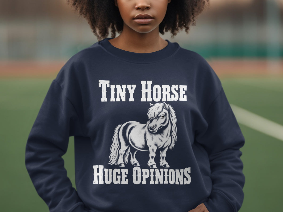 A person wears a dark blue sweatshirt featuring a graphic of a miniature horse with the text Tiny Horse Huge Opinions.