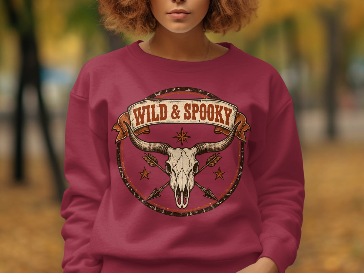 Longhorn skull and arrows graphic with "WILD & SPOOKY" text on a maroon sweatshirt.
