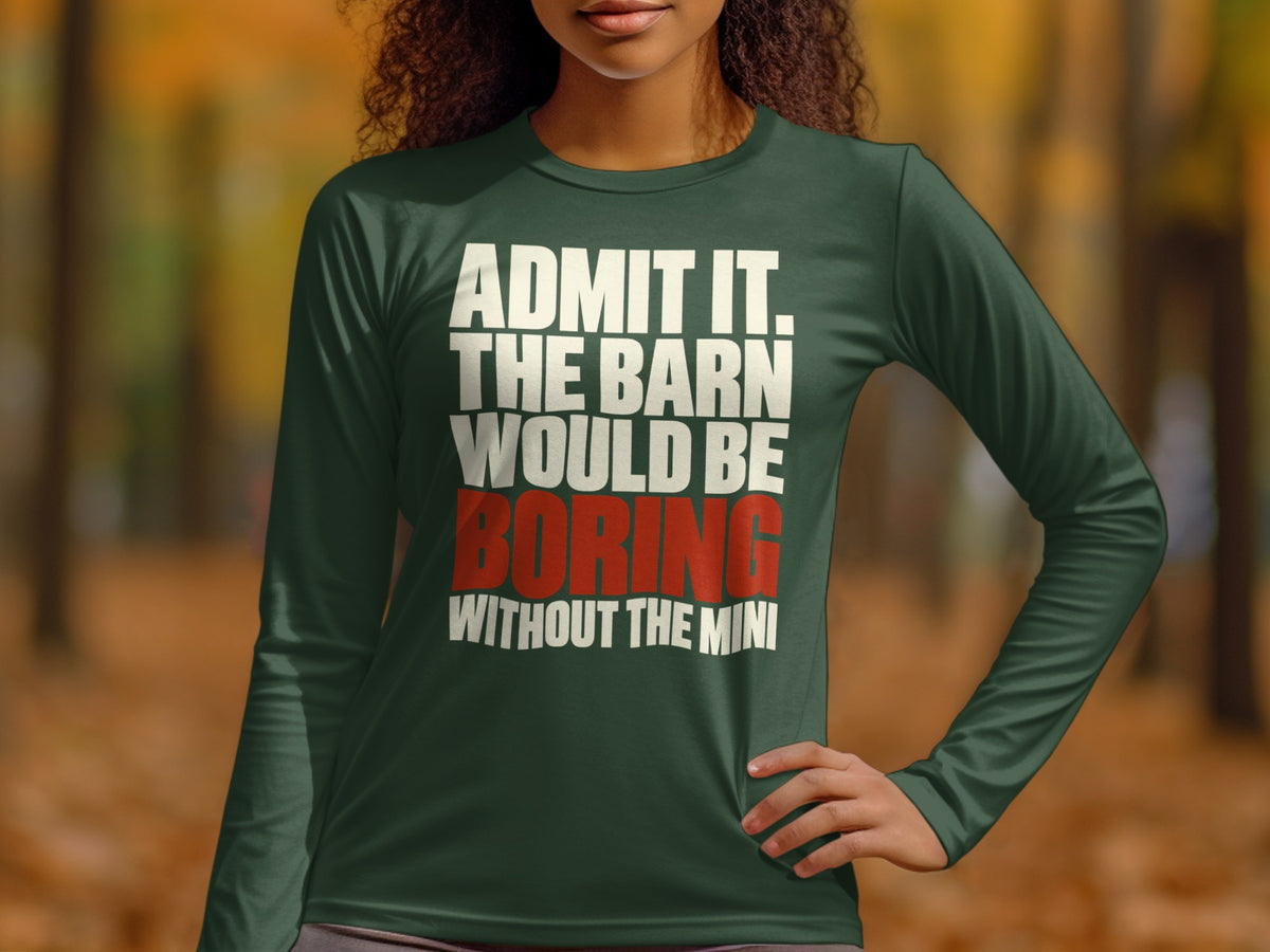 A person wearing a dark green long-sleeve shirt with the white and red text, "Admit it, the barn would be boring without the mini."