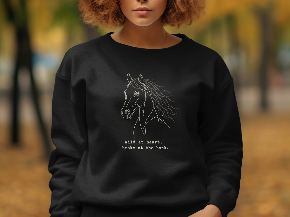 Black sweatshirt with white line art horse and text "wild at heart, broke at the bank."