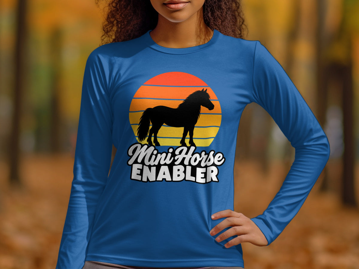 A person wearing a blue long-sleeve shirt featuring a black horse silhouette over a sunset graphic and text.