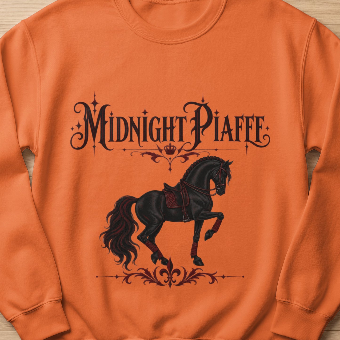 Orange sweatshirt with black text "Midnight Piaffe" and a black horse design.