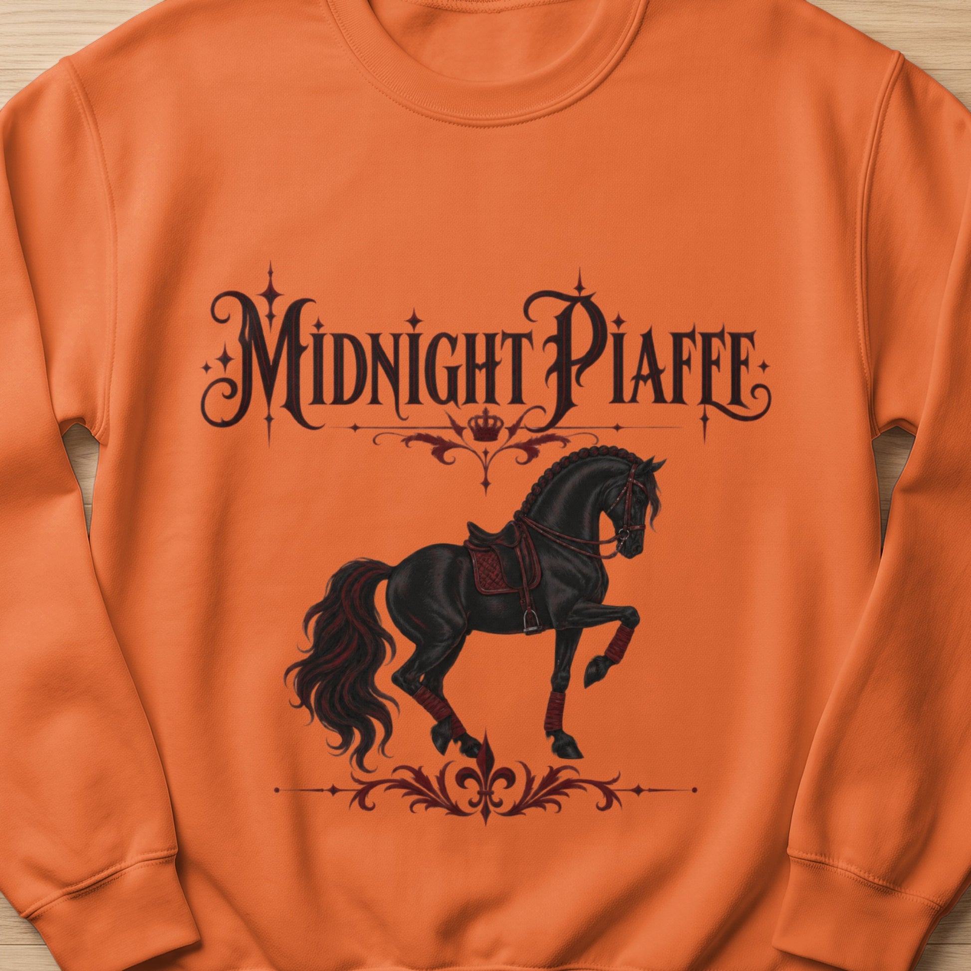 Orange sweatshirt with black text "Midnight Piaffe" and a black horse design.