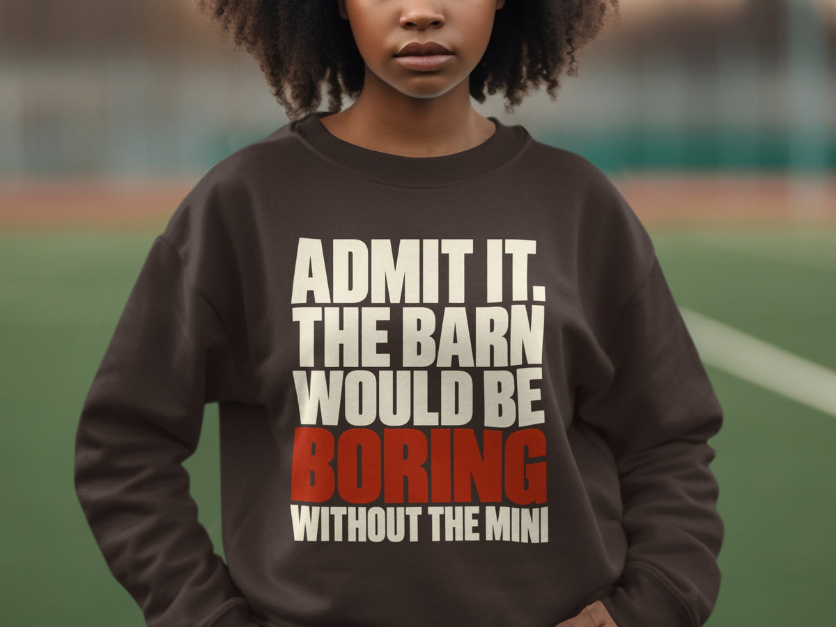 A person wearing a dark brown sweatshirt with white and red text that reads, ADMIT IT. THE BARN WOULD BE BORING WITHOUT THE MINI.