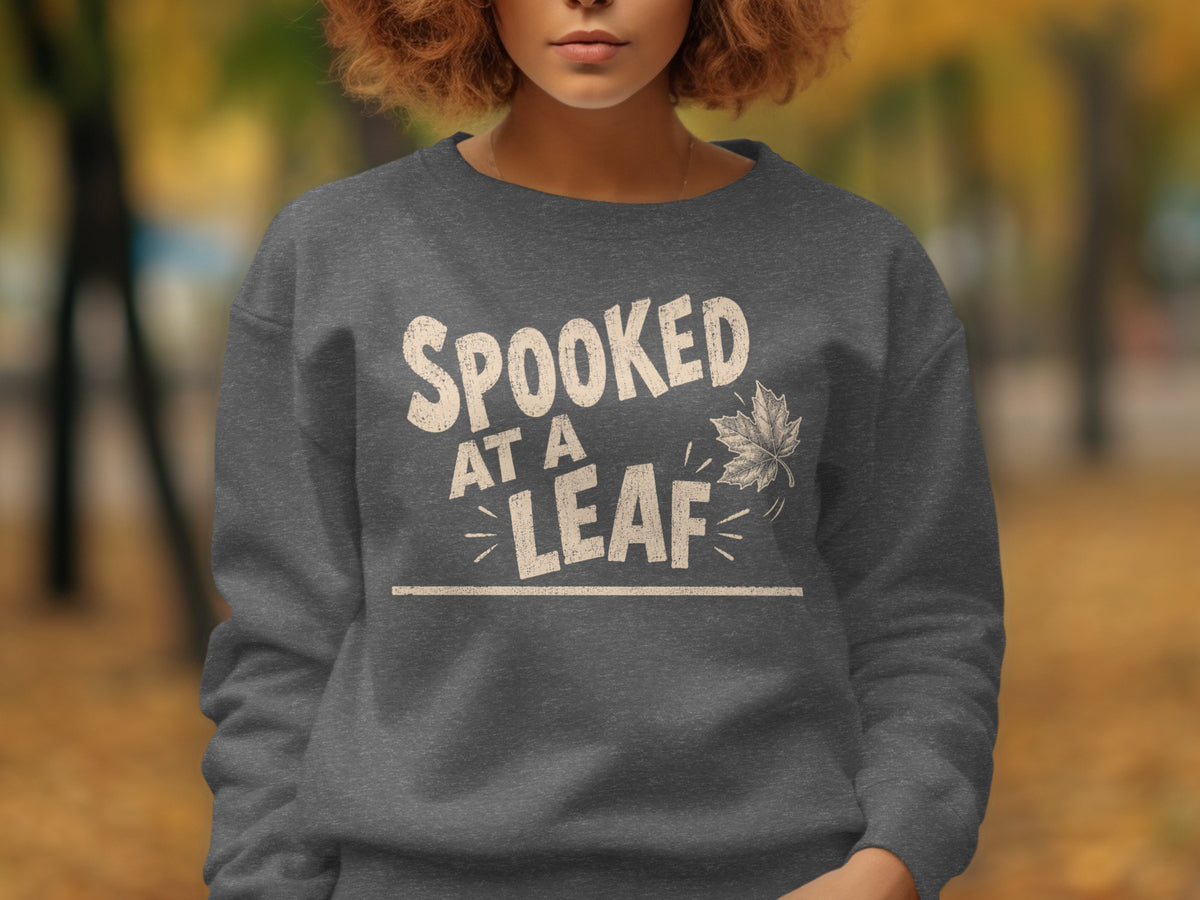 Dark grey sweatshirt with "Spooked At A Leaf" text and a maple leaf graphic.