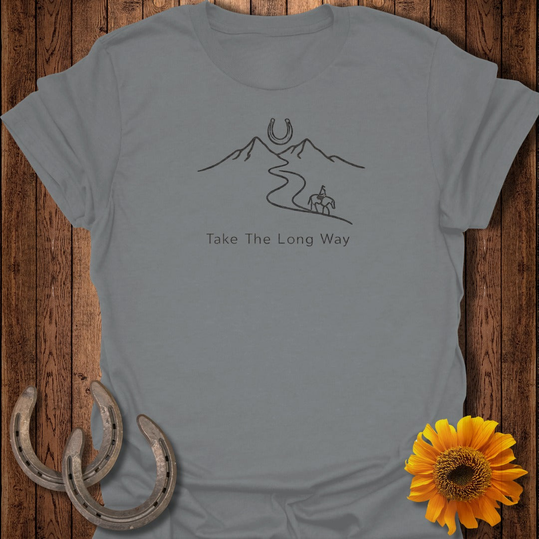 Gray t-shirt with a line drawing of mountains, a winding road, a rider on horseback, and the text "Take The Long Way."