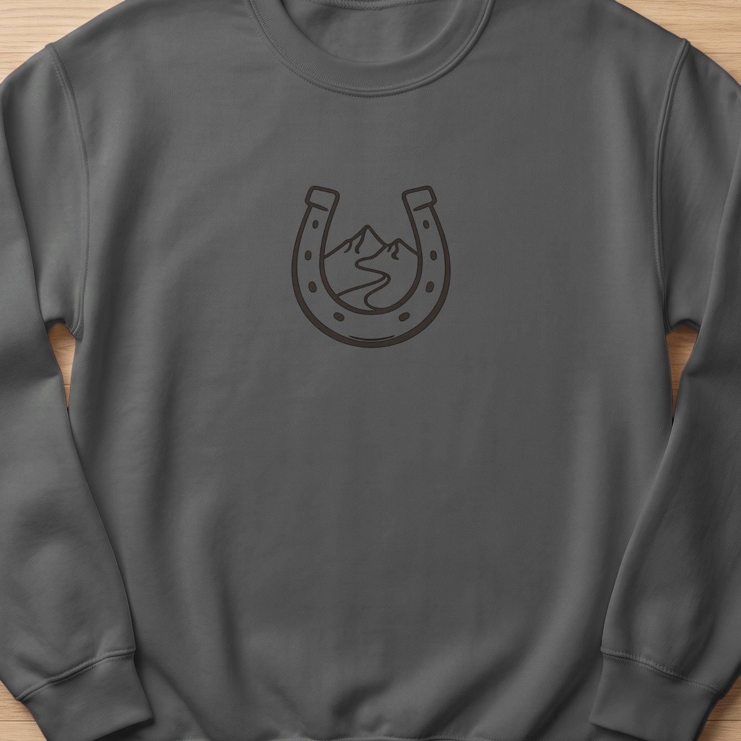 Grey sweatshirt with a dark horseshoe and mountain landscape graphic.