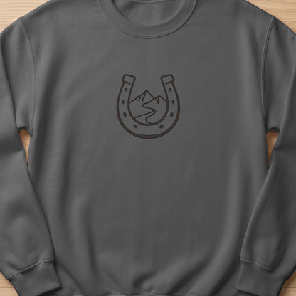 Grey sweatshirt with a dark horseshoe and mountain landscape graphic.