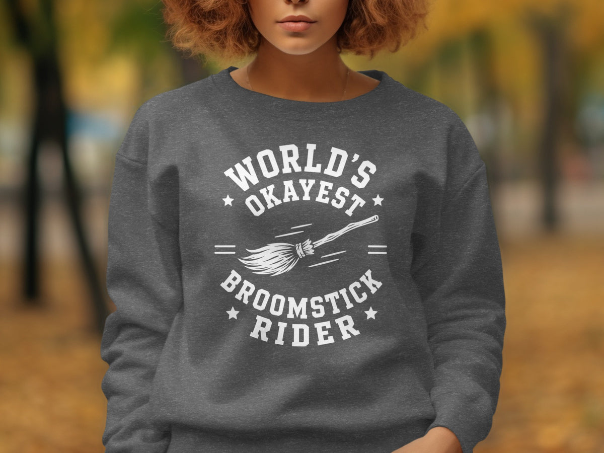 Dark grey sweatshirt with white text "World's Okayest Broomstick Rider" and a broom.