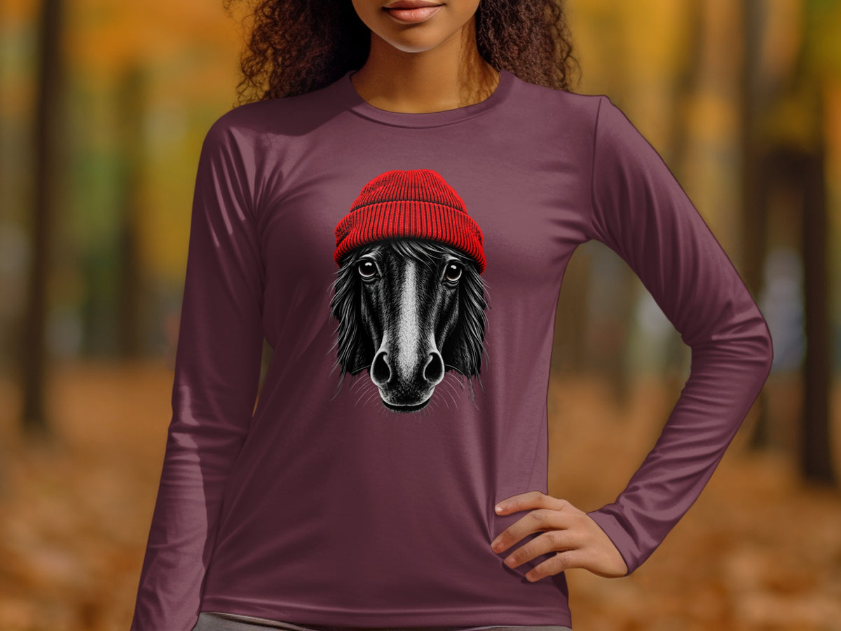 A woman wearing a plum-colored long-sleeve shirt featuring a graphic of a horse in a red beanie.