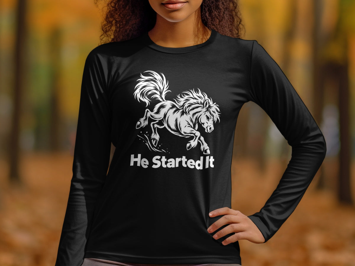 A person wearing a black long-sleeved shirt with a white graphic of a bucking horse and the text He Started It.