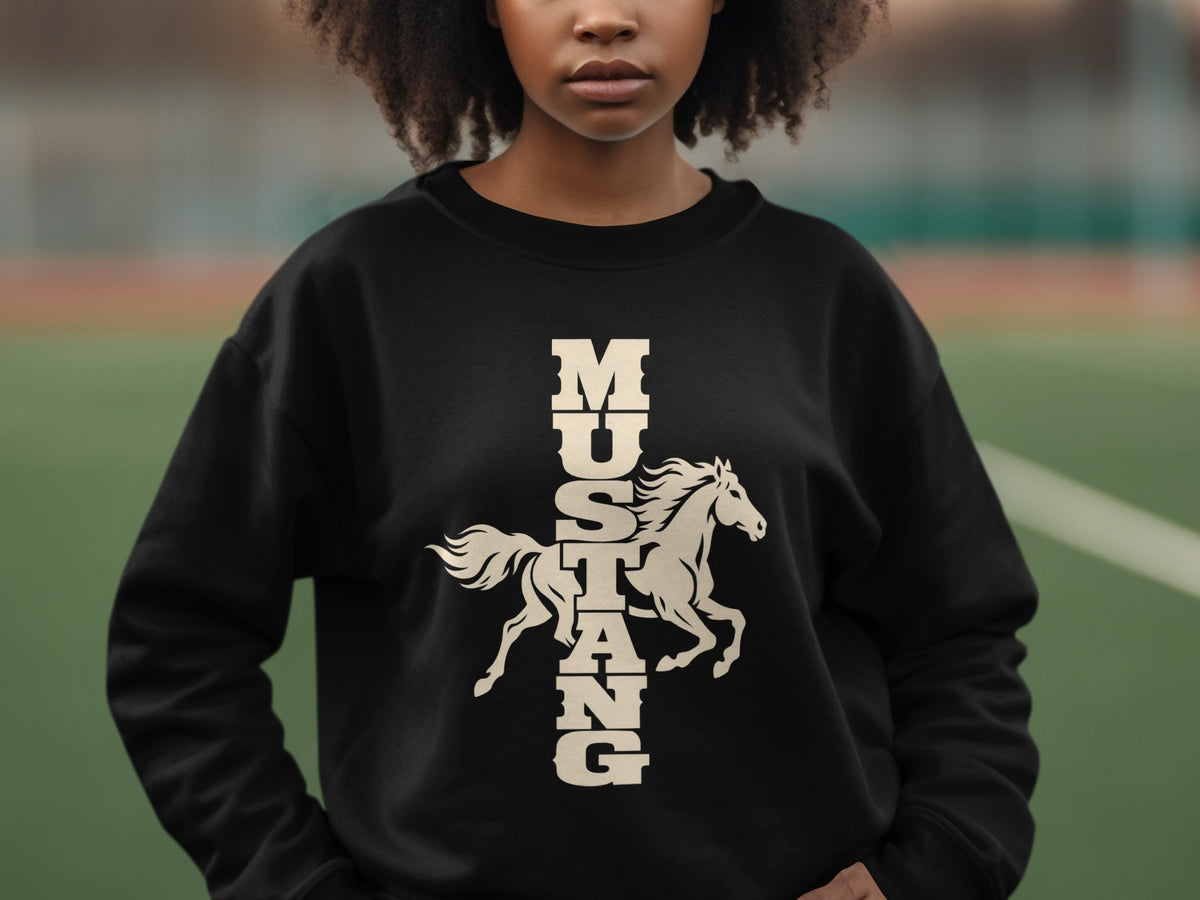 A person wearing a black crewneck sweatshirt featuring a cream graphic of a galloping horse and the vertical text MUSTANG.