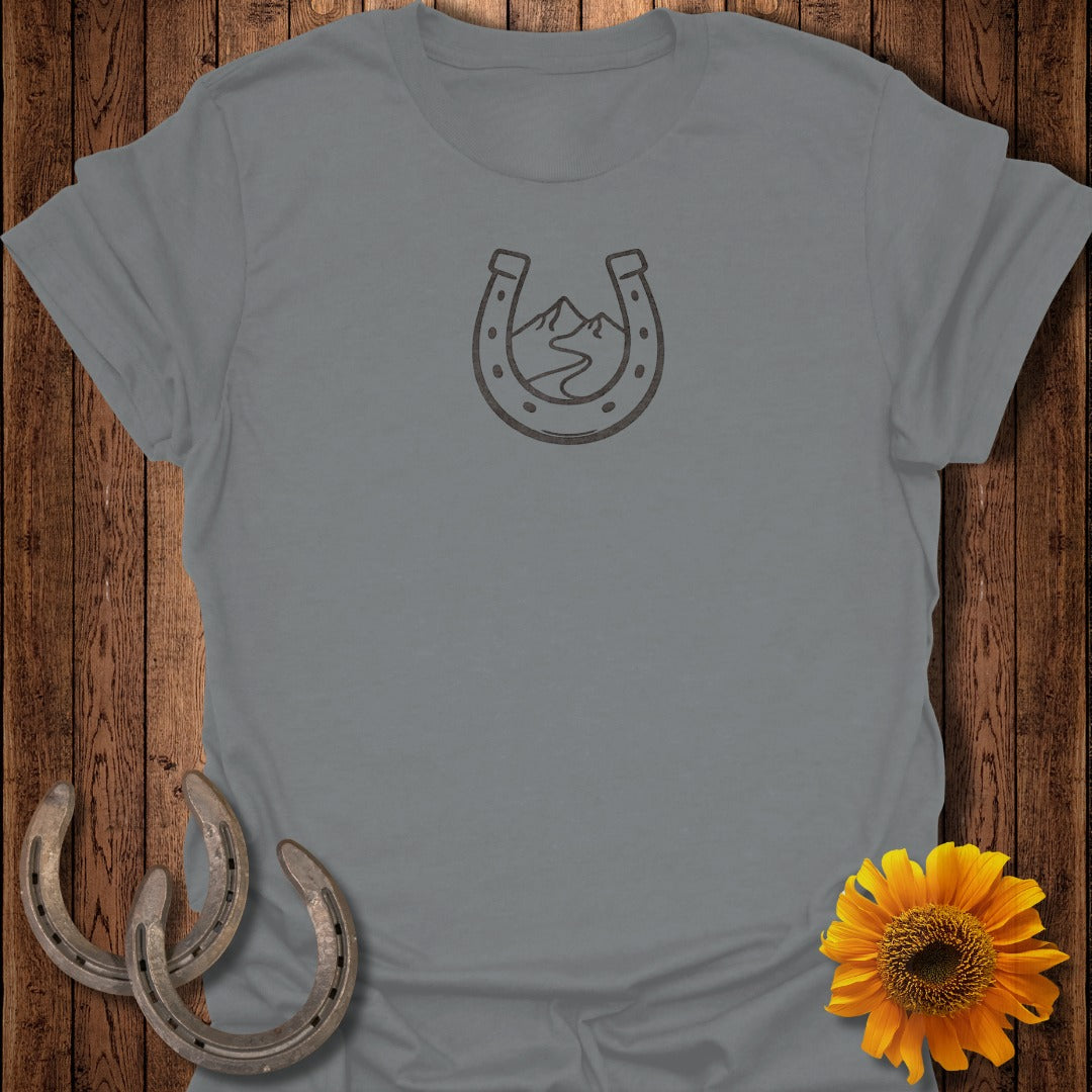 Grey t-shirt with a horseshoe graphic containing mountains and a winding road.