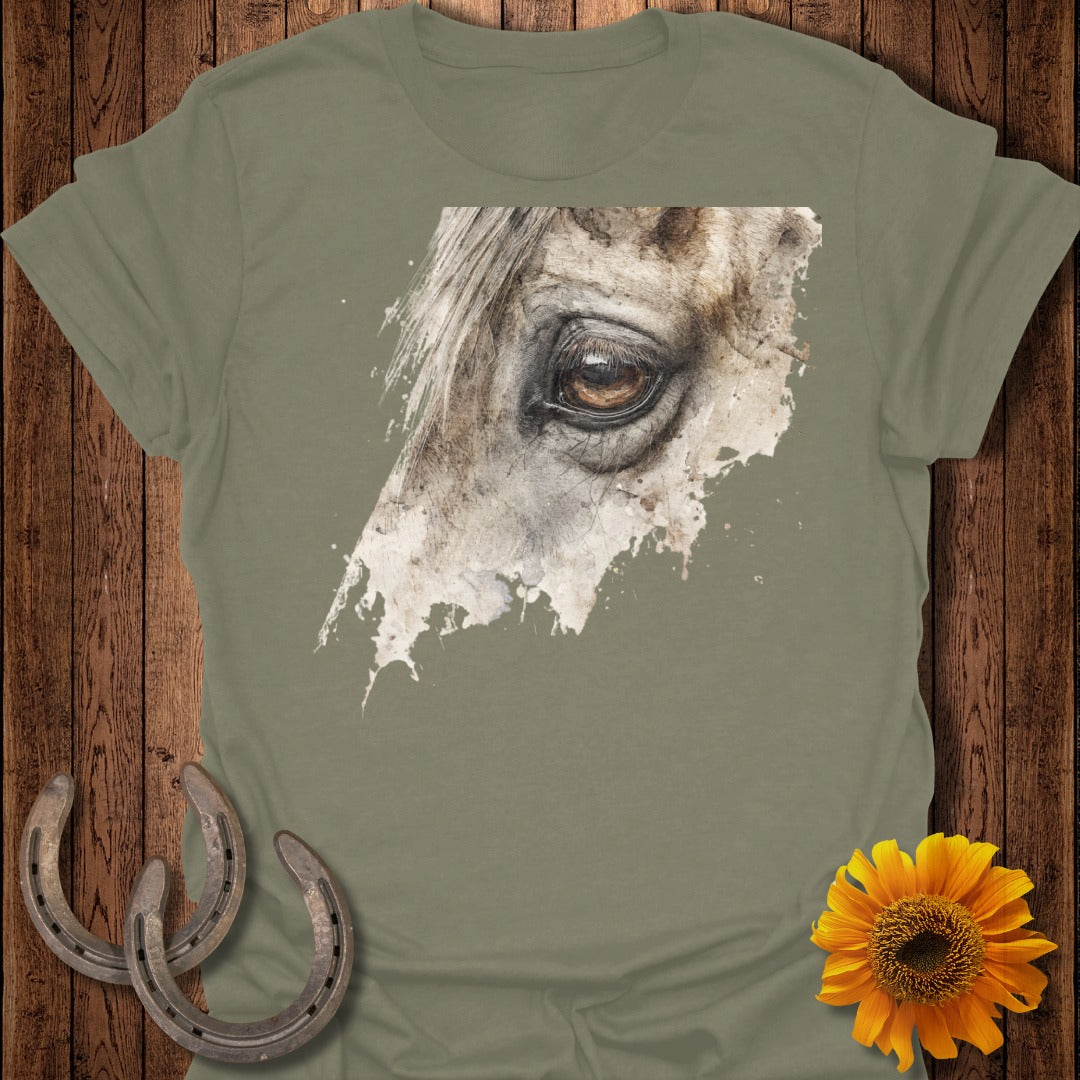 Close-up of a horse's eye on a taupe t-shirt, with horseshoes and sunflower.