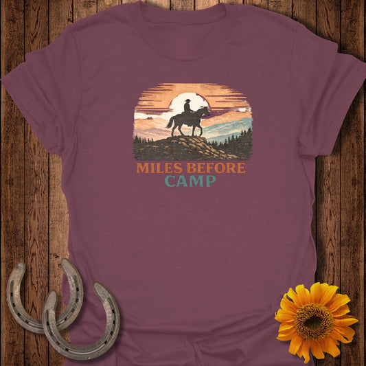 Maroon t-shirt with "Miles Before Camp" text and a horse rider silhouetted against a sunset landscape.