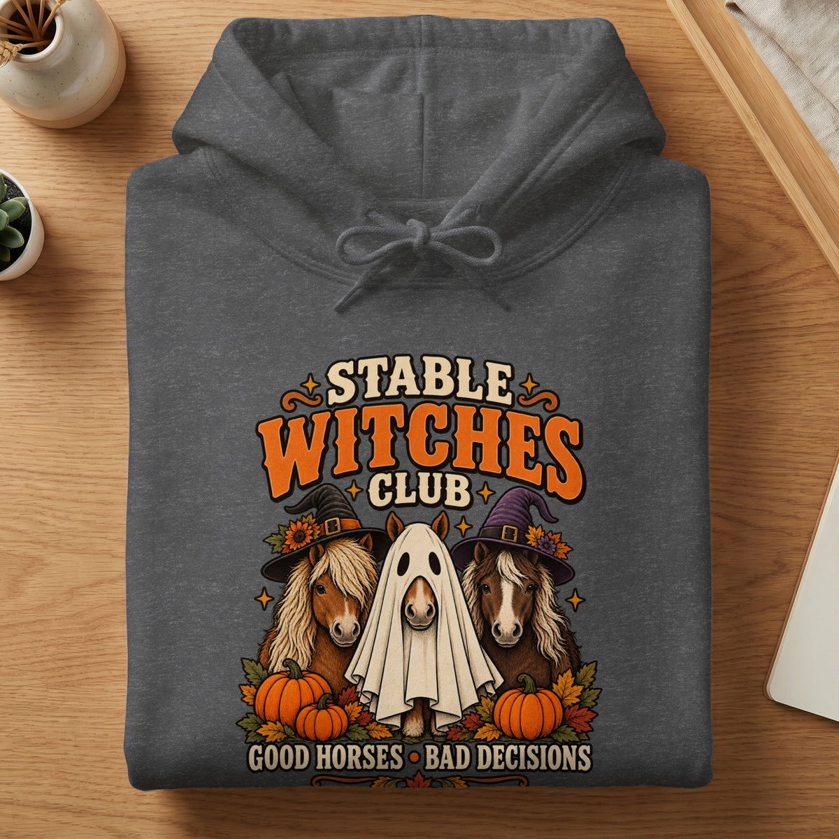 Dark gray hoodie with Halloween graphic of horses, pumpkins, and text "Stable Witches Club".