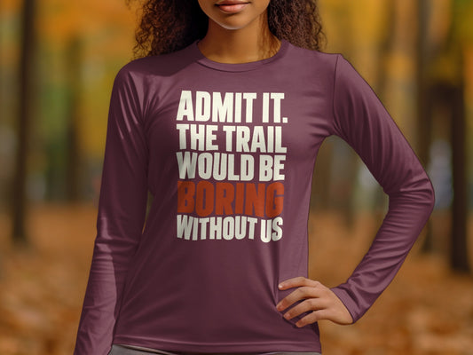 A person wearing a maroon long-sleeve shirt with white and orange text that reads "Admit it, the trail would be boring without us."