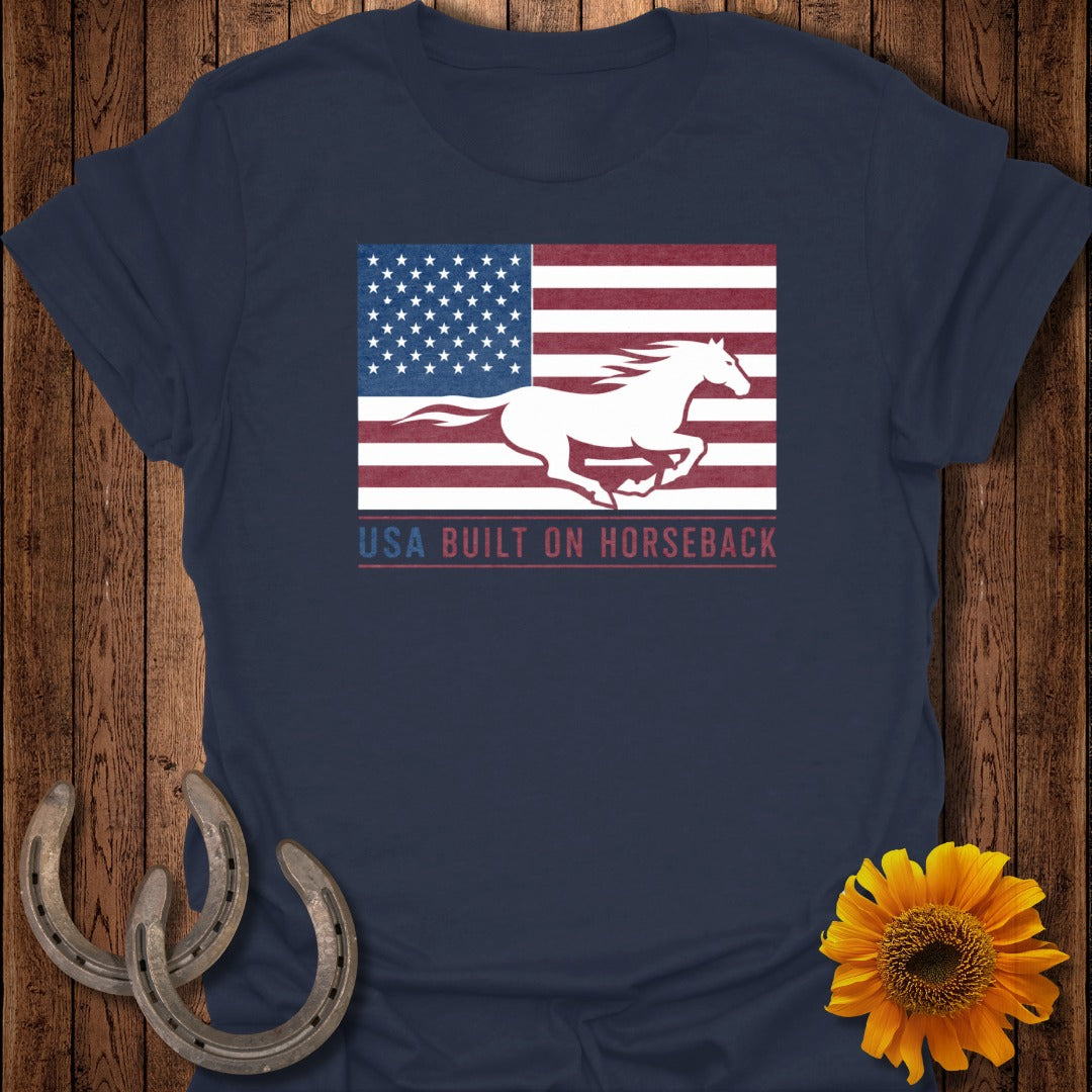 Dark blue t-shirt with white horse running across US flag; text reads "USA BUILT ON HORSEBACK".