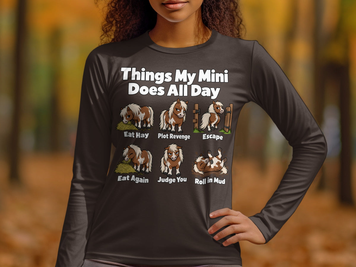 A person wearing a dark grey long-sleeve shirt with humorous illustrations and text about miniature horses.