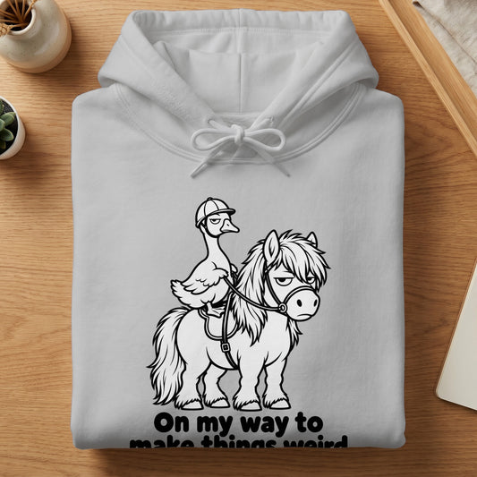 White hoodie with cartoon goose riding a grumpy pony, text reads "On my way to make things weird".