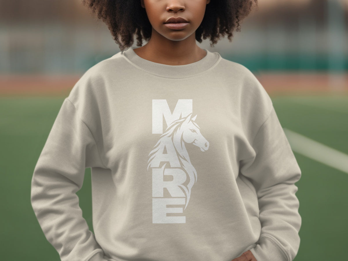 A person wearing a beige crewneck sweatshirt with the word MARE and a horse graphic on the front.