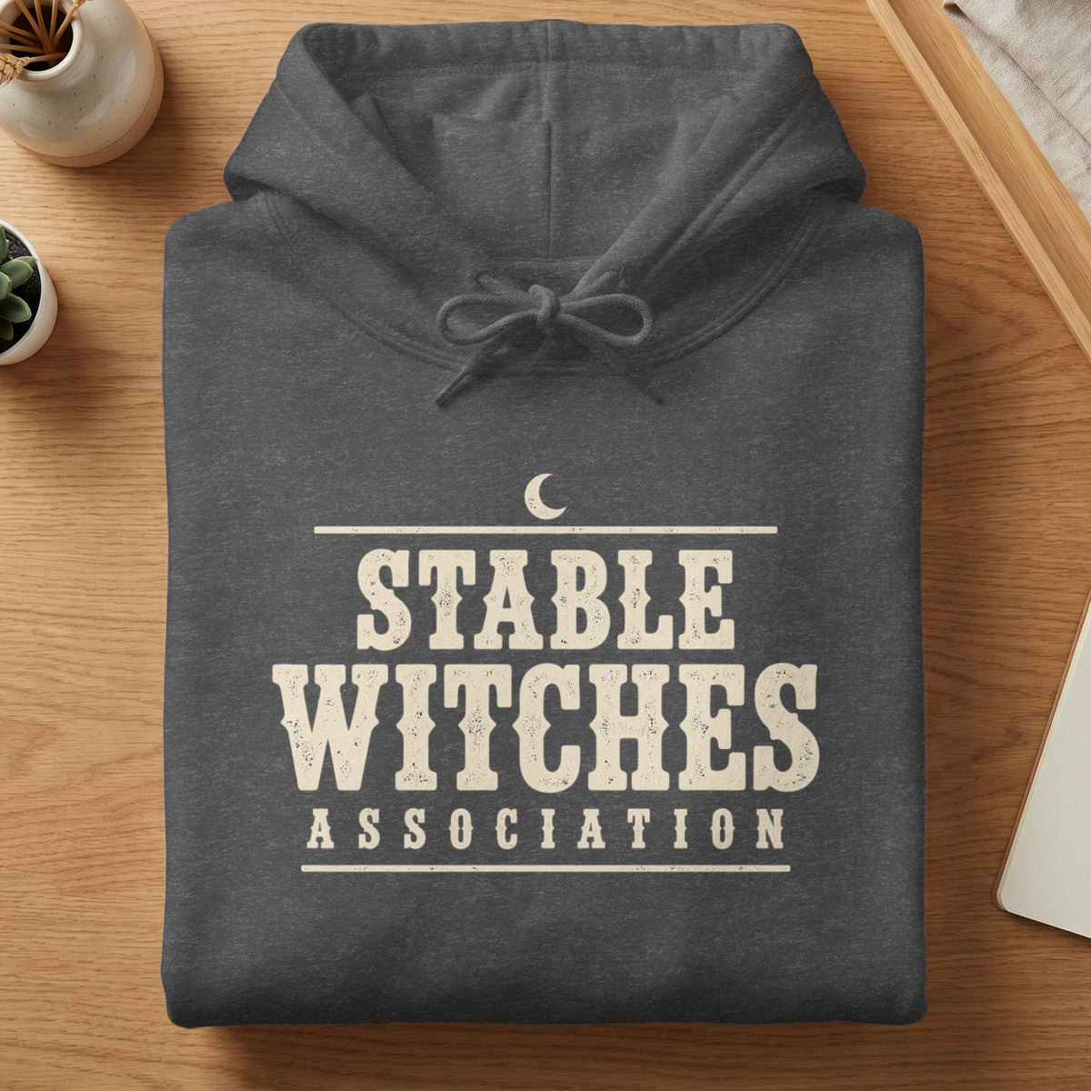 Dark grey hoodie with "STABLE WITCHES ASSOCIATION" text and a crescent moon graphic.