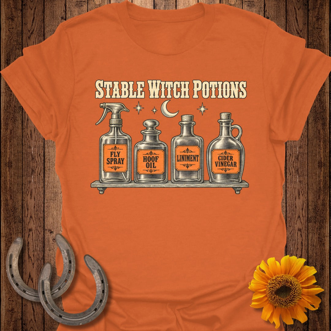 Orange t-shirt with "Stable Witch Potions" and four bottles: Fly Spray, Hoof Oil, Liniment, Cider Vinegar.