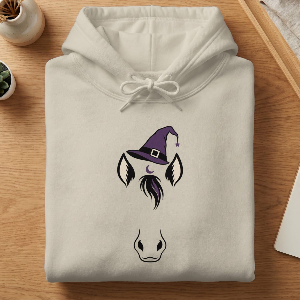 Cream hoodie with a purple witch hat and horse face graphic.