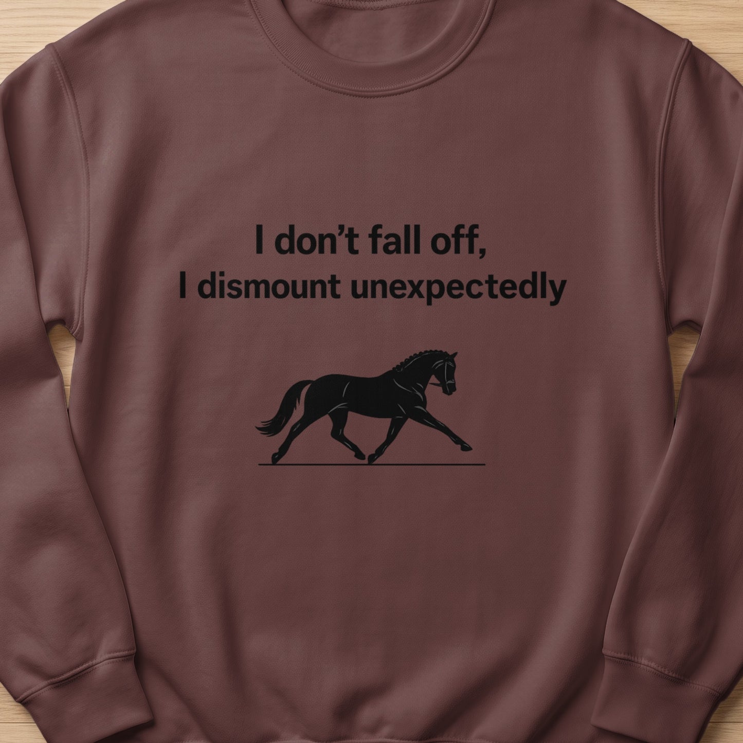 Brown sweatshirt with text "I don't fall off, I dismount unexpectedly" and horse graphic.