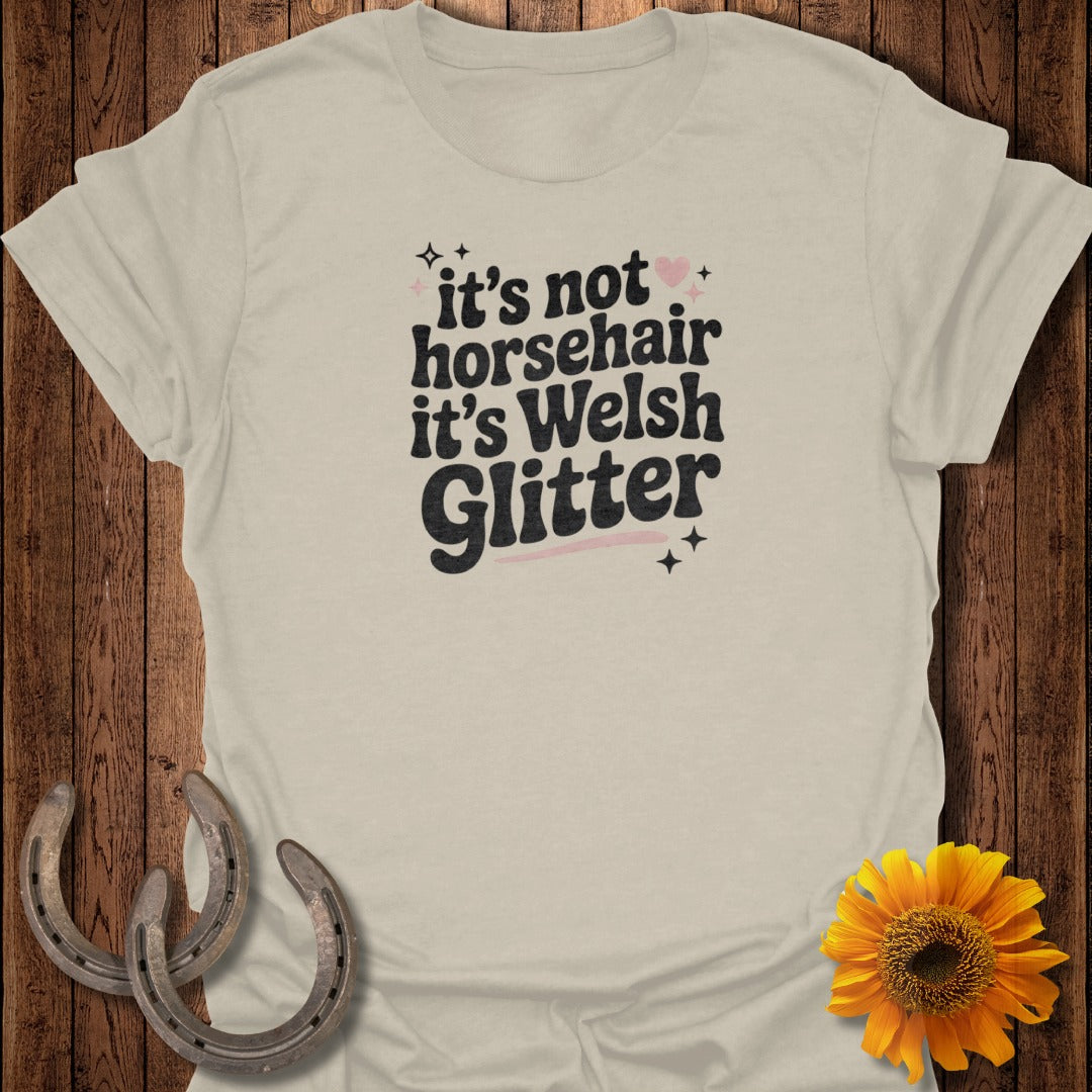 Light beige t-shirt with "it's not horsehair it's Welsh Glitter" text and pink hearts.