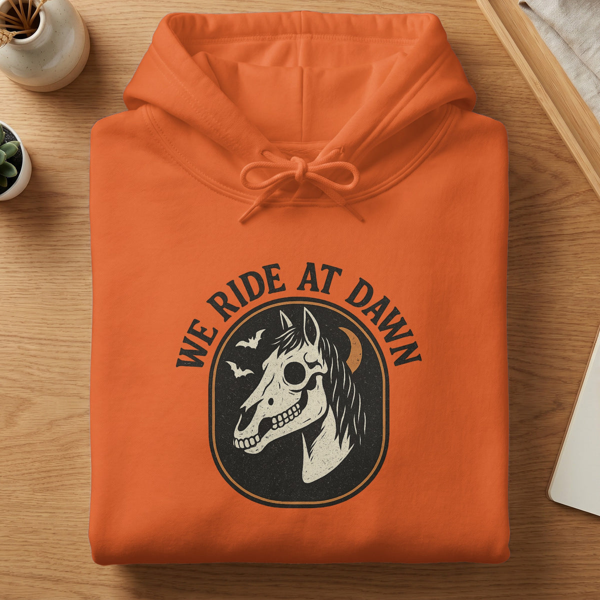 Orange hoodie with a graphic of a horse skull, bats, and crescent moon.