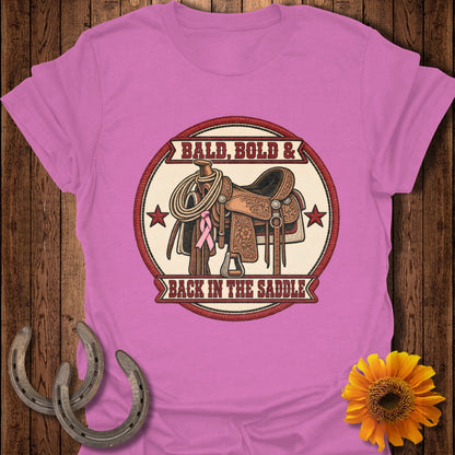 Pink t-shirt with rodeo saddle graphic and text "Bald, Bold & Back in the Saddle".