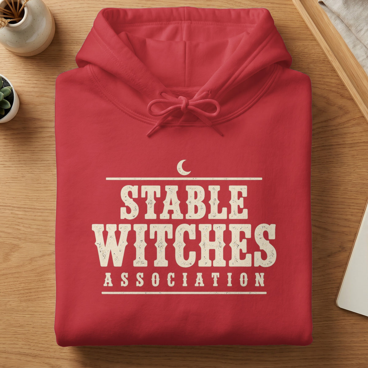 Red hoodie with "STABLE WITCHES ASSOCIATION" text and a crescent moon graphic.