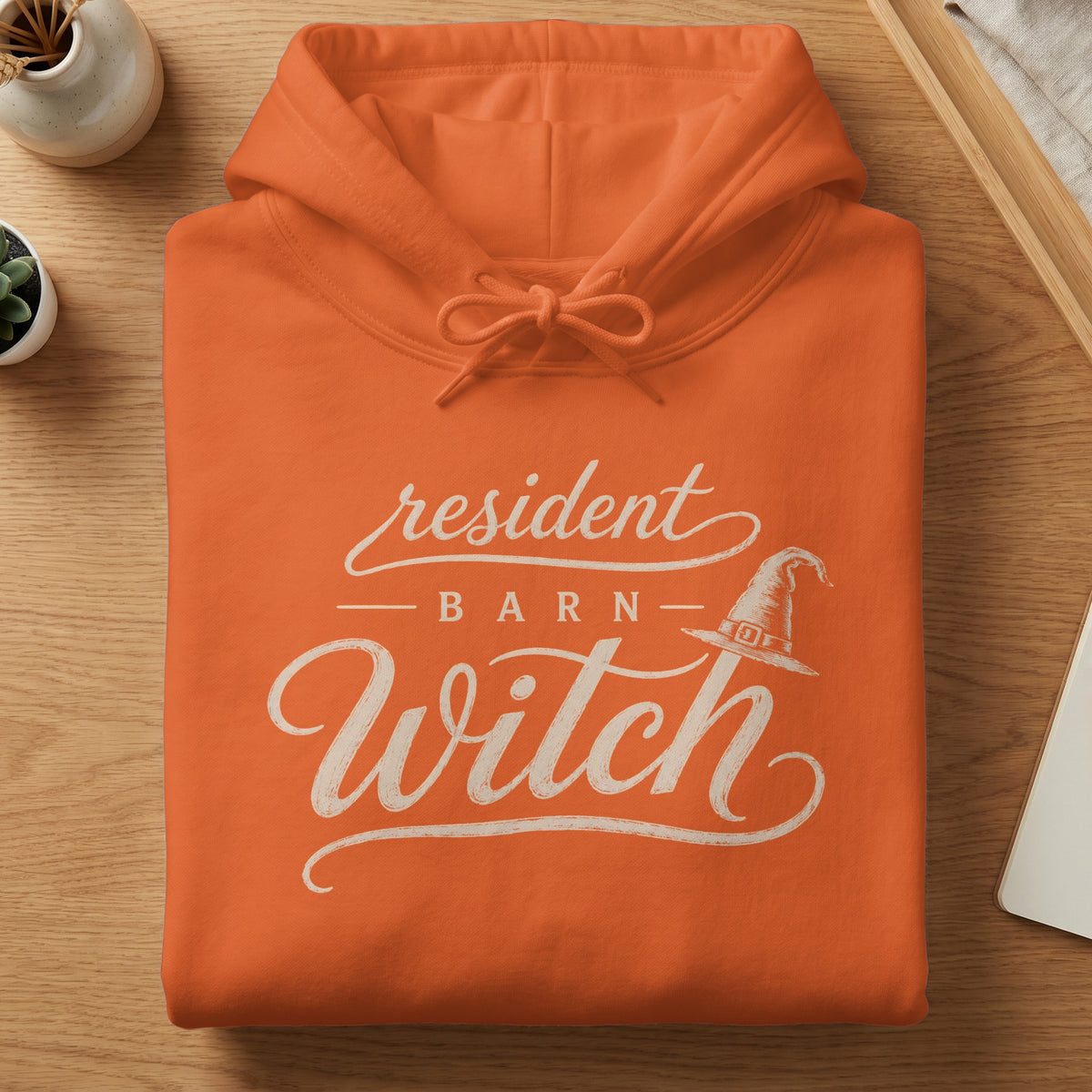 Orange hoodie with "Resident Barn Witch" text and witch hat graphic.