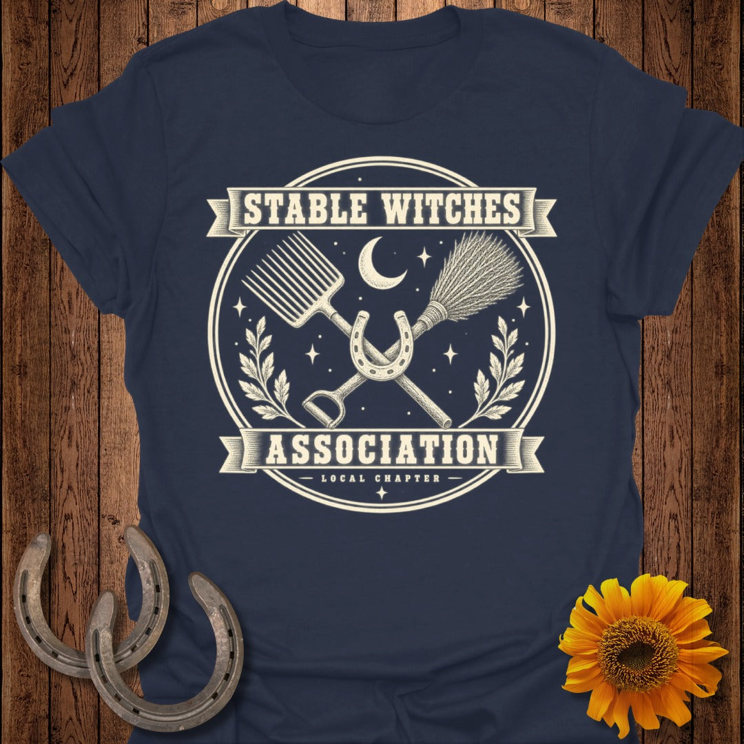 Dark blue t-shirt with "Stable Witches Association" text and witchy stable imagery.