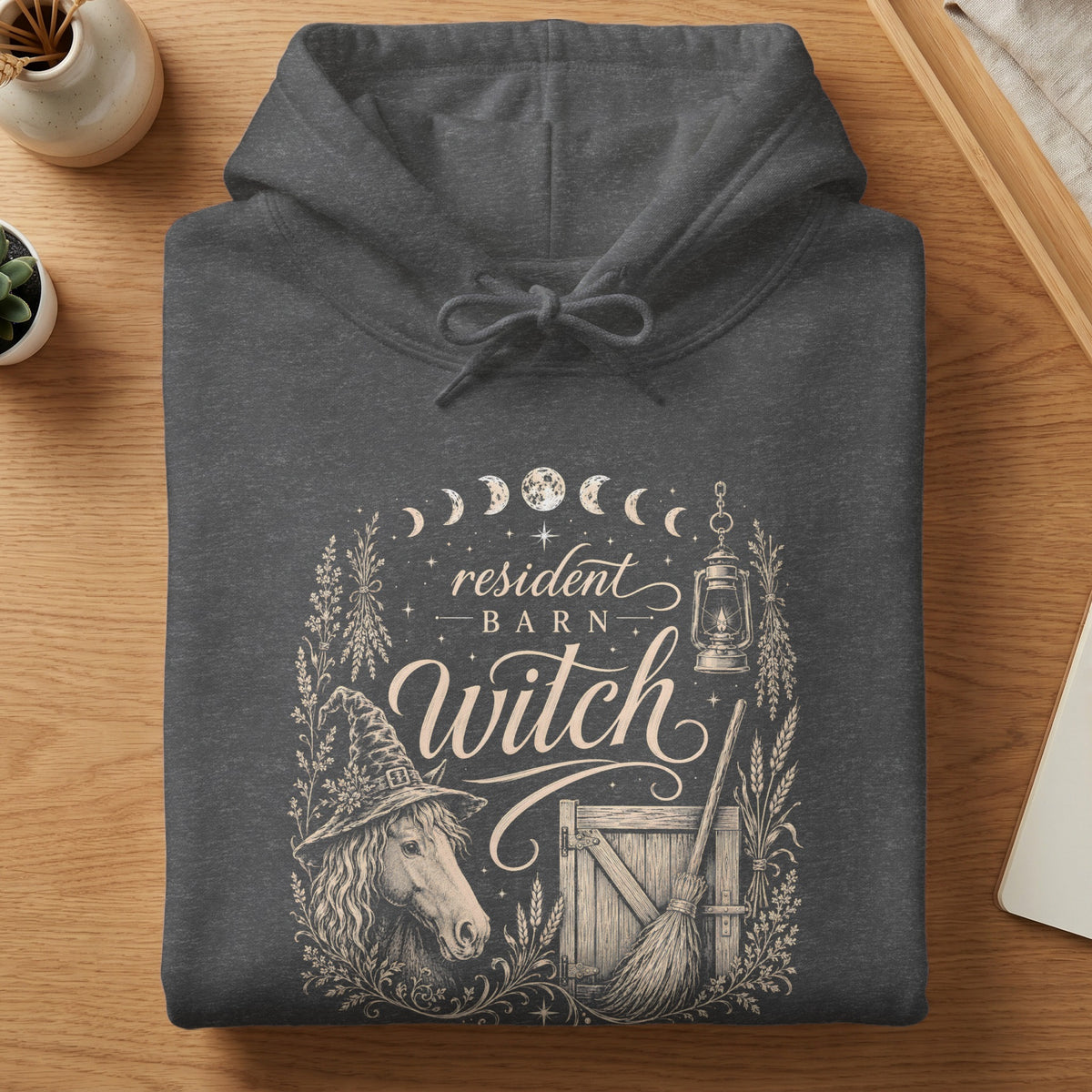 Dark gray hoodie with "resident barn witch" graphic featuring a horse, broom, and barn door.