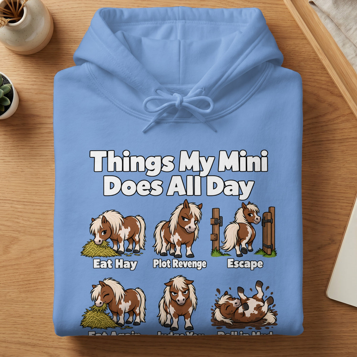 Light blue hoodie featuring humorous illustrations of miniature horses and the text Things My Mini Does All Day.